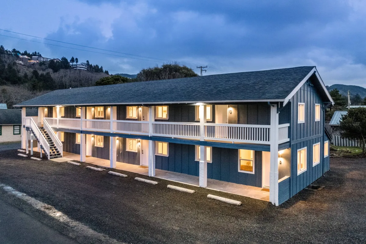 A welcoming exterior shot of the multi-story inn, with warm lighting glowing from the windows and visible balconies where guests can socialize or enjoy the view. The building's approachable design suggests an easy connection to the area’s attractions.