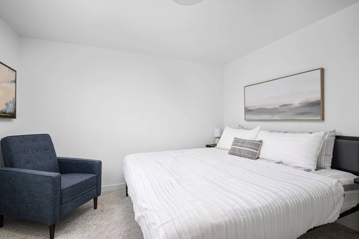 A serene interior space featuring a cozy bed, an inviting armchair, and tasteful artwork on the wall. The room is well-lit and calming, with surfaces and furnishings that appear easy to clean—ideal for guests traveling with pets.
